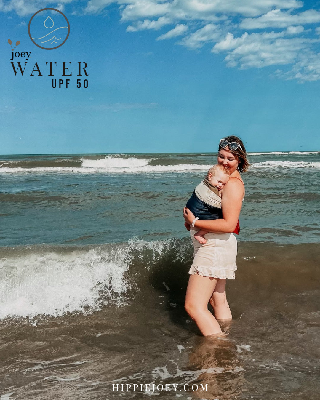 Joey Water ( A waterproof simple, stretchy Sling/ Wrap/ baby carrier type assistant garment)  being used on the beach to keep baby happy while standing in ocean